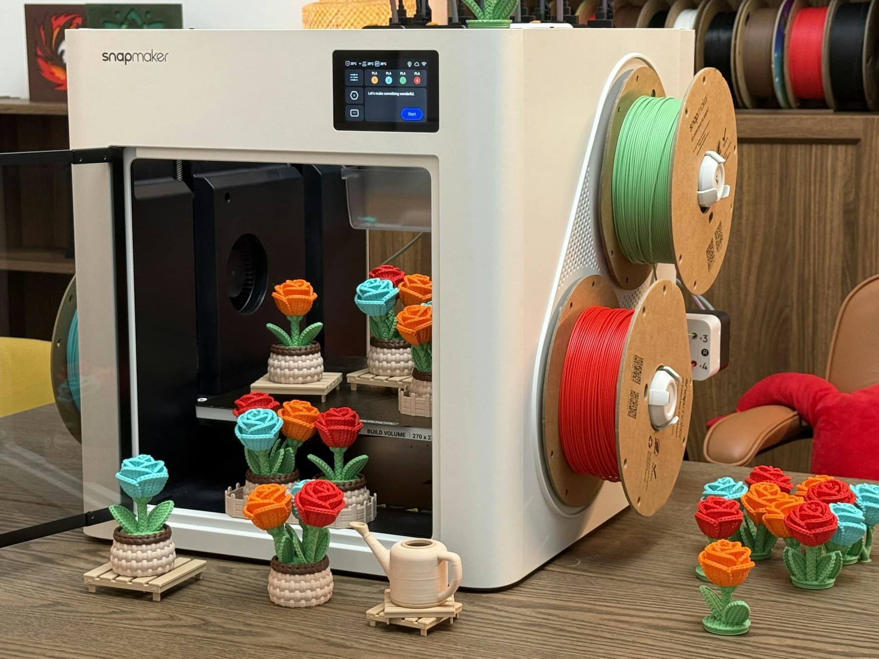Desktop 3D printer working with filament spools and printed objects
